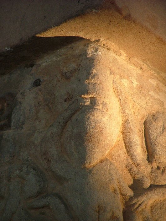 Close up of the sheela's head and corner mask. Note the faint suggestion of eyes on the sheela's head and what appears to be hair on the left hand side.